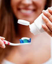 Woman squeezing toothpaste onto a standard toothbrush