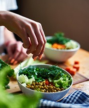 Hands with orange nails making salads in bowls