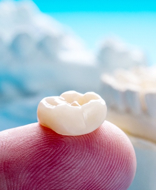 Closeup of dental crown in Newport on finger