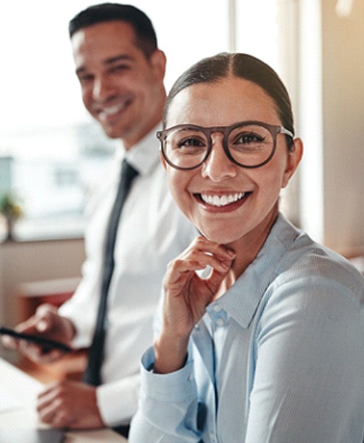 Woman smiling with dental crown in Newport at workplace