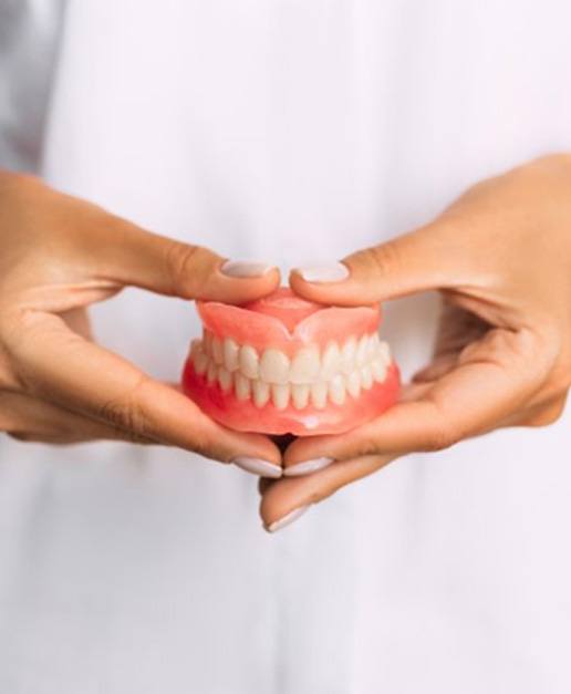 a person holding a pair of newly created dentures