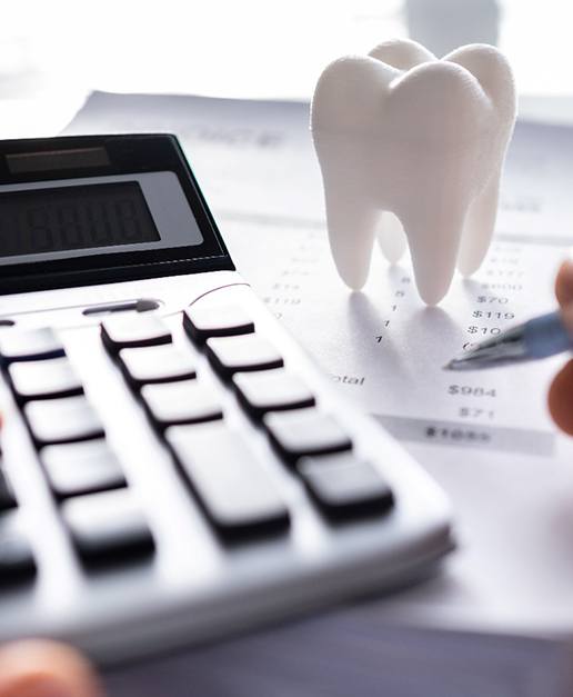 a calculator with a model of a tooth next to it