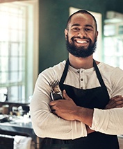 a smiling man with an apron on at a restaurant
