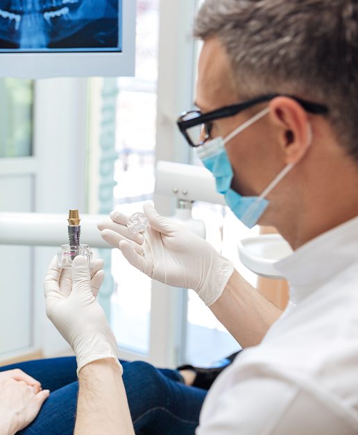 Dentist showing patient a dental implant post
