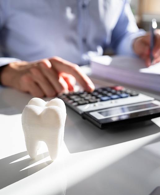 Person using calculator to determine dental insurance coverage