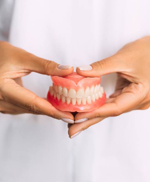 Hands holding full set of dentures