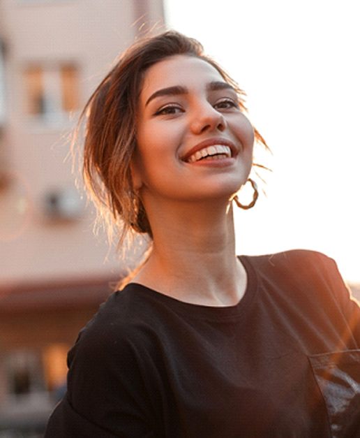 Woman walking on the street and smiling after emergency dentistry