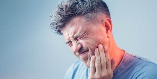 Man in need of emergency dentistry holding jaw in pain