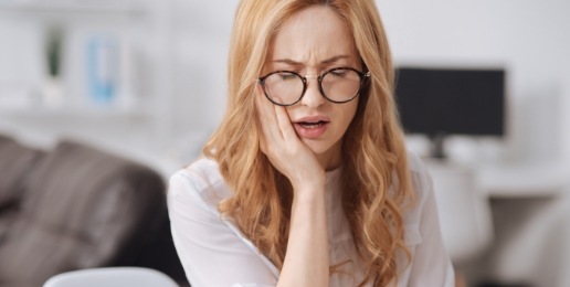 Woman in need of periodontal therapy holding jaw