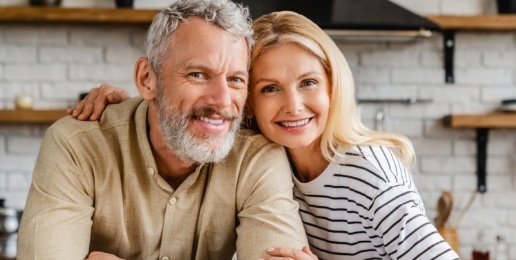 Man and woman smiling after replacing missing teeth