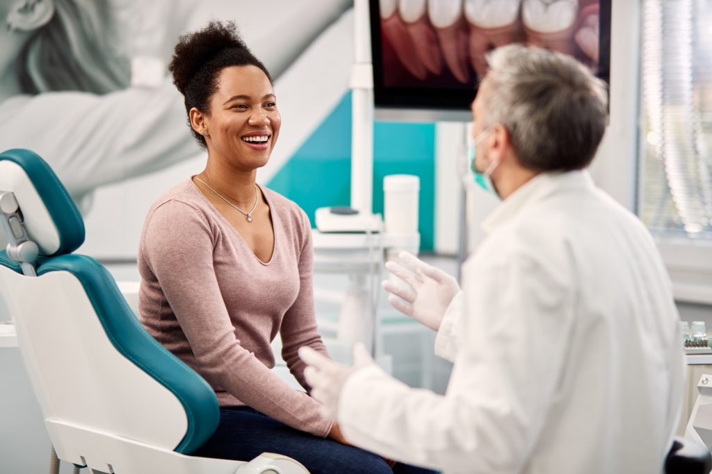 Woman smiling while talking to dentist at checkup